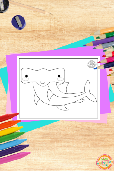 Free printable hammerhead shark coloring page on wooden background with coloring supplies- kids activities blog
